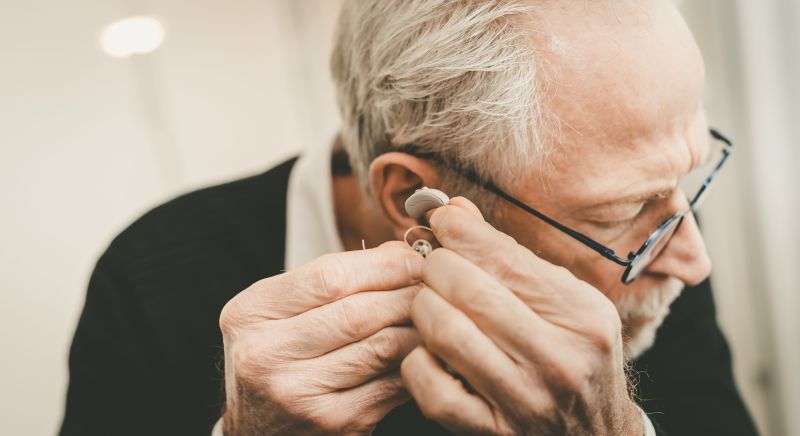 Old man puts in hearing aid