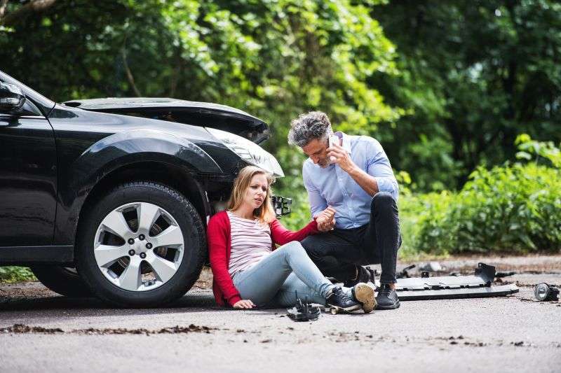 Young woman after accident with man making call